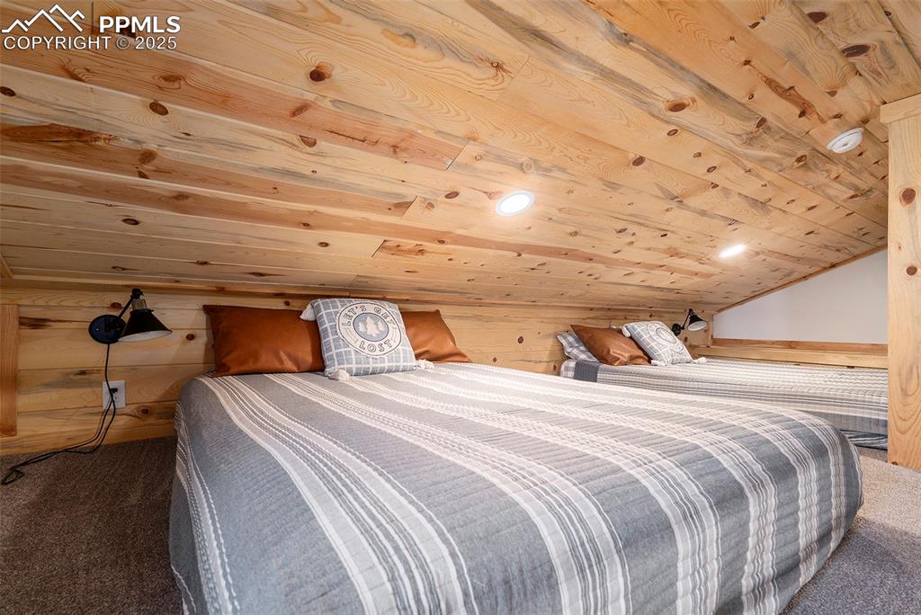 Image 16 of 25: Carpeted bedroom featuring wooden ceiling and lofted ceiling