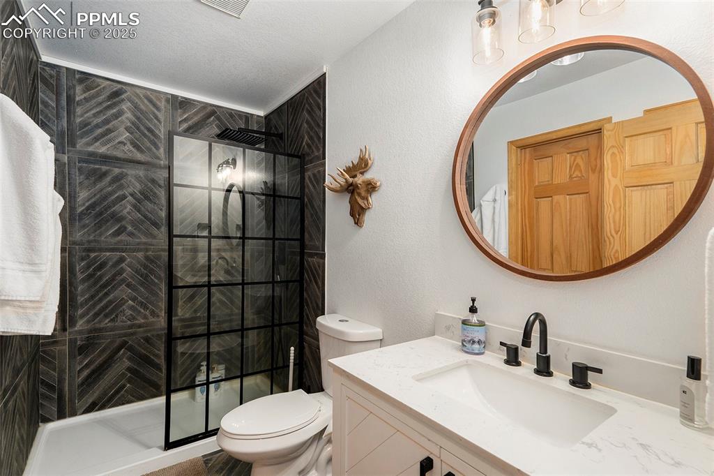Image 18 of 25: Bathroom with walk in shower, vanity, and a textured wall