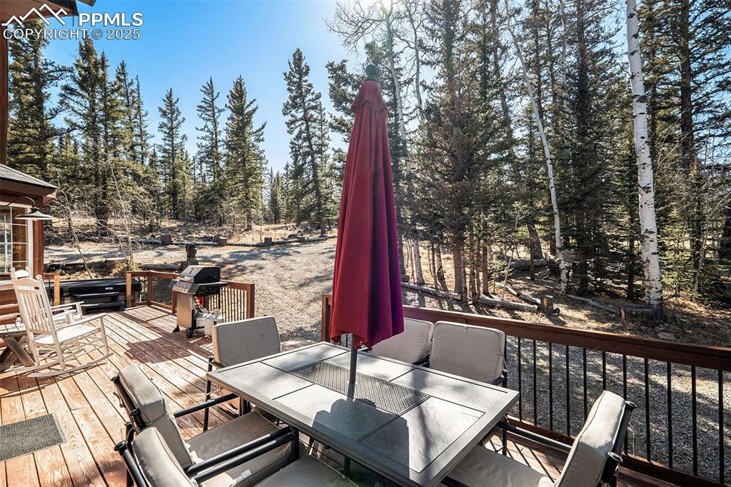 Image 21 of 25: Wooden deck with outdoor dining space and grilling area