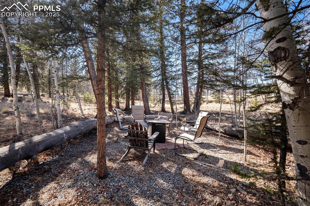 Image 24 of 25: View of yard with an outdoor fire pit, view of scattered trees, and a patio