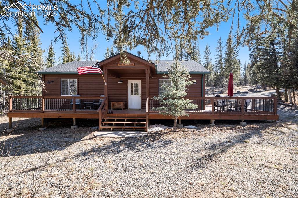 Image 3 of 25: View of front of house featuring a deck, a shingled roof, and log veneer si