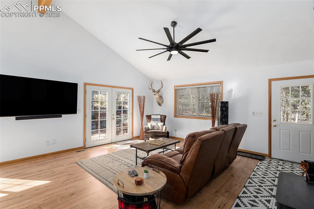 Image 6 of 25: Living area with high vaulted ceiling, wood-type flooring, french doors, an