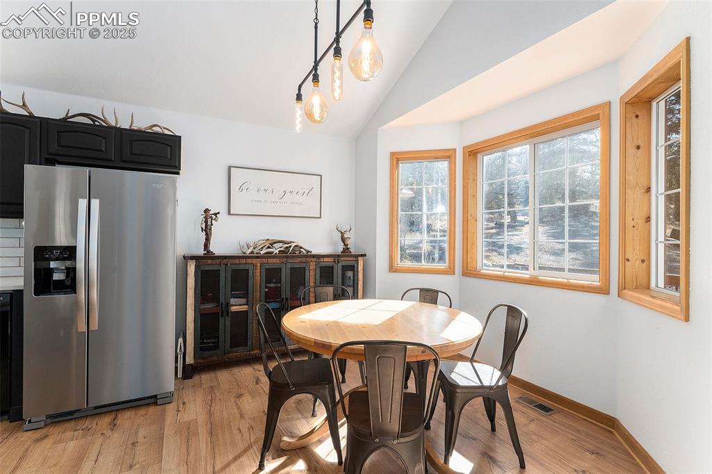 Image 8 of 25: Dining room with light wood finished floors and lofted ceiling