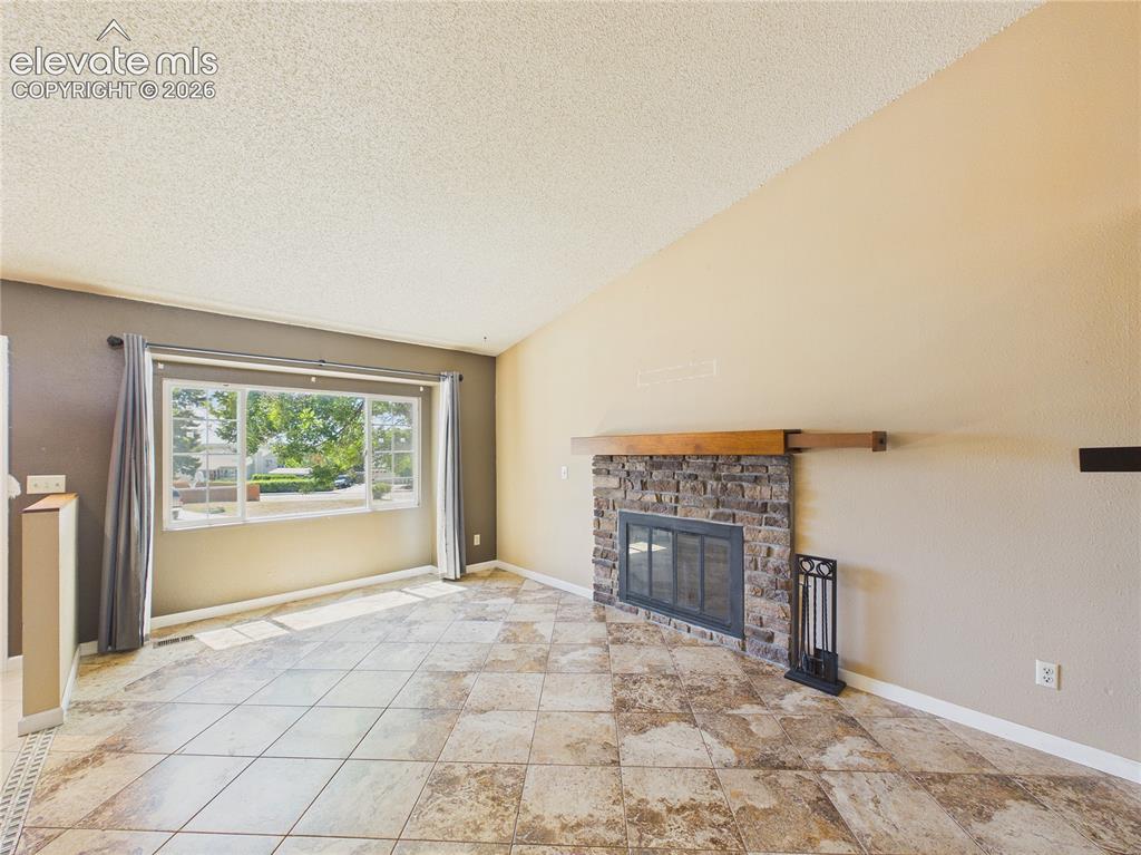 Image 10 of 46: Inviting living room featuring a striking brick fireplace, tile flooring, a