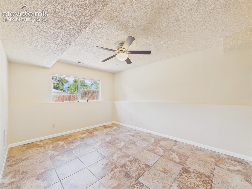 Image 24 of 46: Spacious living area with tile flooring, ceiling fan, and easy flow into th