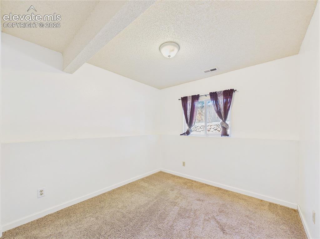 Image 28 of 46: Bright bedroom with carpeting, natural light, and easy access to the home