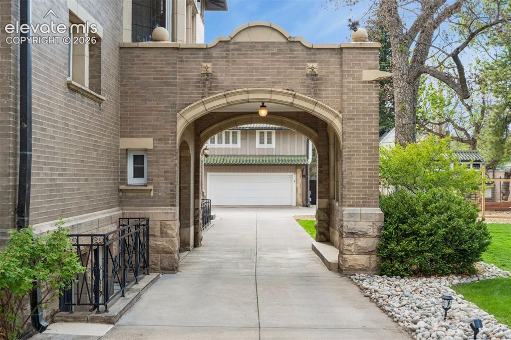 Image 37 of 50: Grand portico leading to carriage house and garage. Heated driveway.