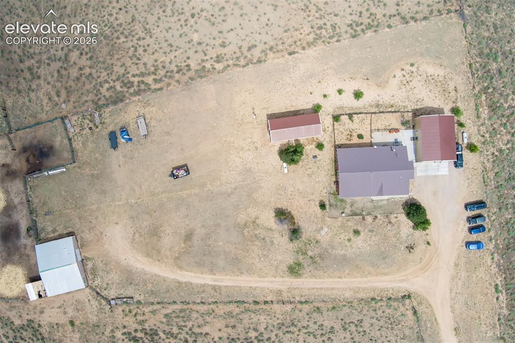 Image 45 of 45: View of homesite and out buildings to include garage, RV building and barn.