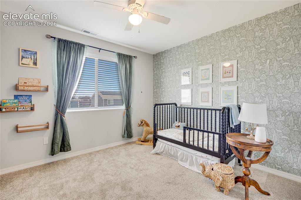 Image 11 of 42: Room with patterned accent wall, neutral-toned carpeting, and a window with