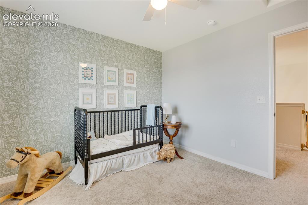 Image 12 of 42: Bedroom featuring patterned accent wall, neutral carpeting, and a ceiling f