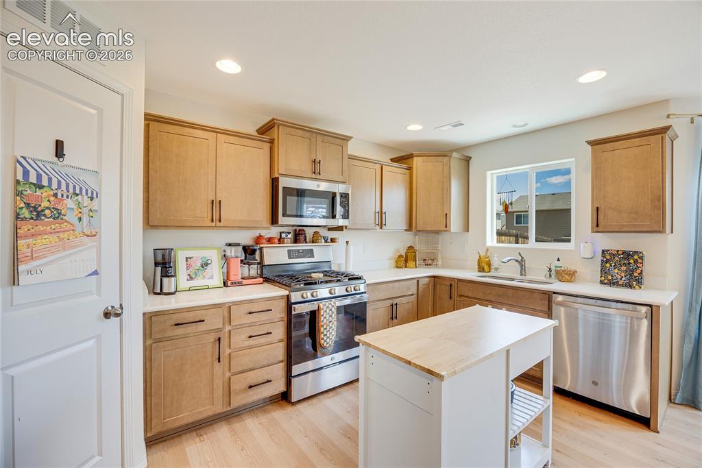 Image 15 of 42: Kitchen featuring a central mobile island with a butcher block top, stainle
