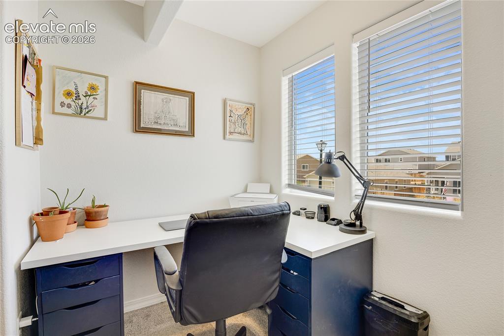 Image 19 of 42: Bright interior workspace featuring two windows with horizontal blinds, car