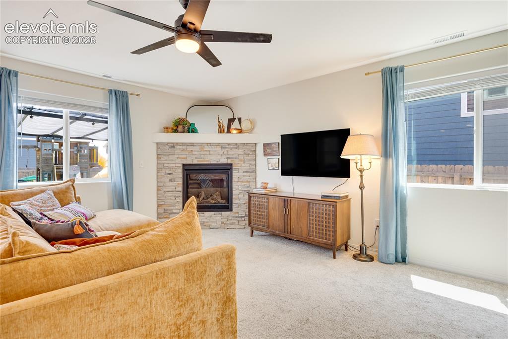 Image 2 of 42: Living area featuring a stone-faced fireplace with a mantel, light-colored