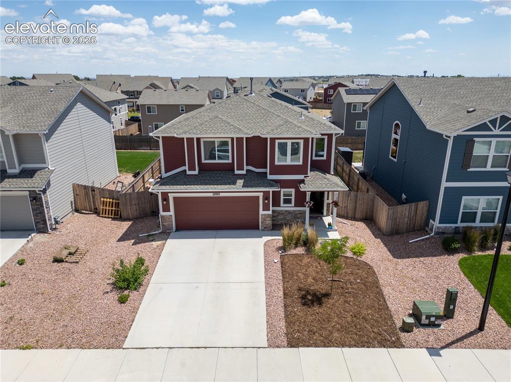 Image 23 of 42: Two-story residence featuring a two-car garage, stone accents, and a red ex