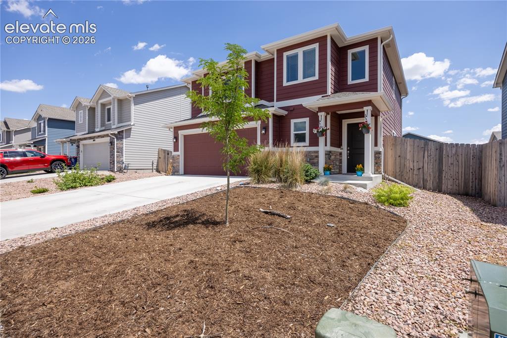 Image 32 of 42: Two-story residence featuring a dark red facade with white trim, an attache