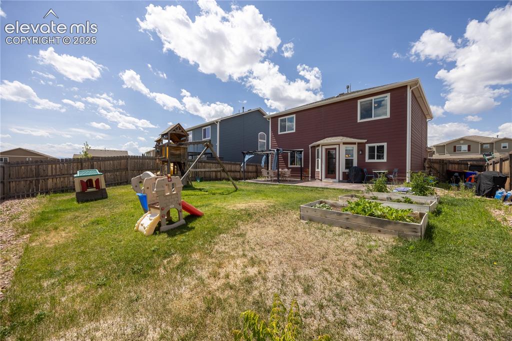 Image 33 of 42: Expansive backyard featuring a fenced perimeter, raised garden beds, a grou