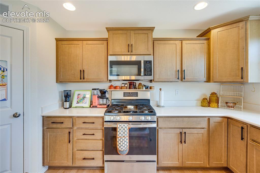 Image 35 of 42: Well-appointed kitchen featuring light-toned wood cabinetry with dark hardw