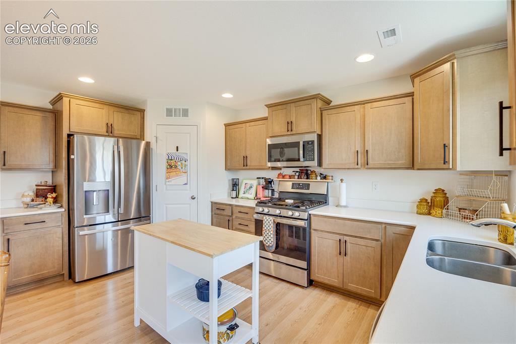 Image 4 of 42: Modern kitchen featuring light wood-finish cabinetry, stainless steel appli