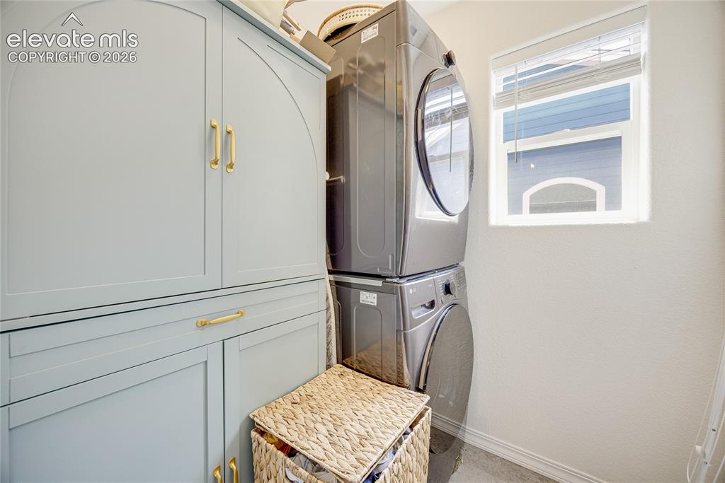 Image 40 of 42: Built-in light blue cabinetry with gold hardware, stacked washer and dryer,