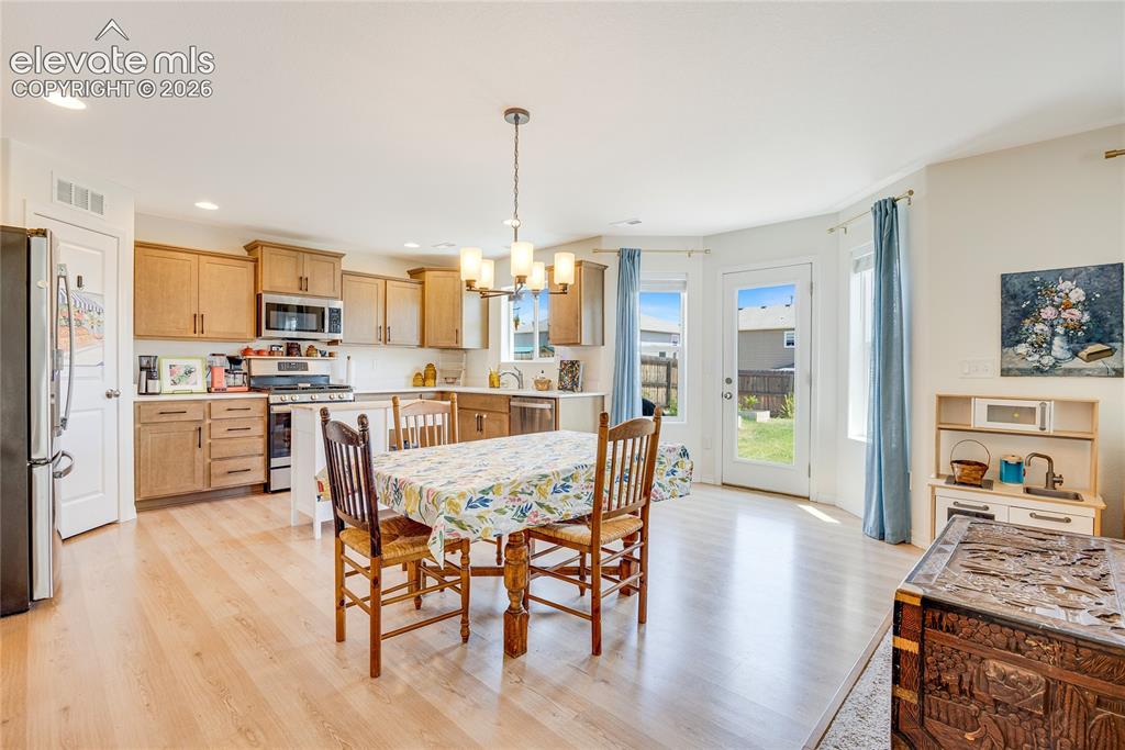 Image 5 of 42: Open-concept kitchen and dining area featuring light wood-finish flooring,