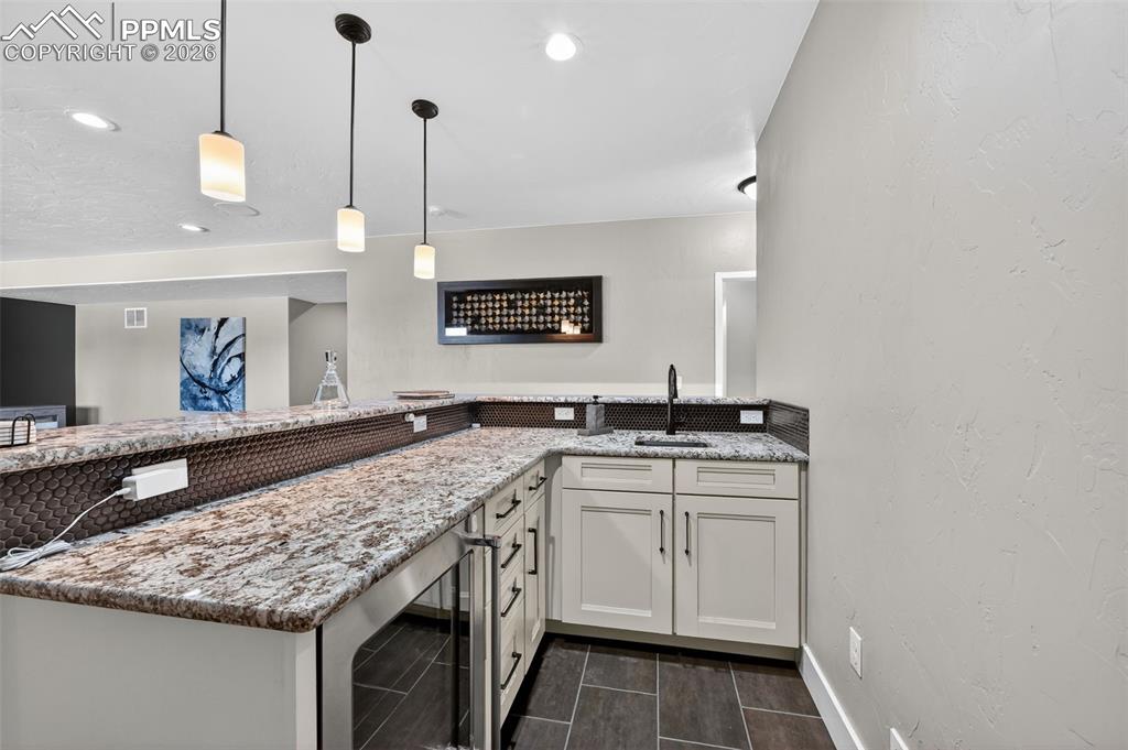 Image 43 of 50: wet bar in lower level includes sink, beverage refrigerator and plenty of s