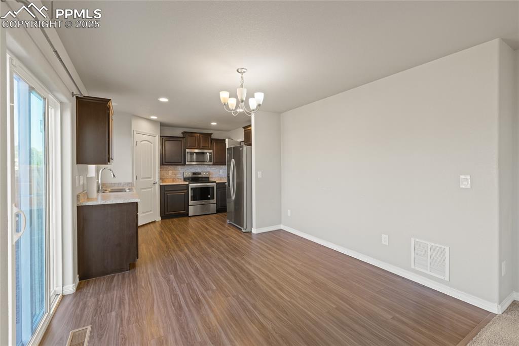 Image 10 of 24: Kitchen with light countertops, dark brown cabinetry, a chandelier, stainle