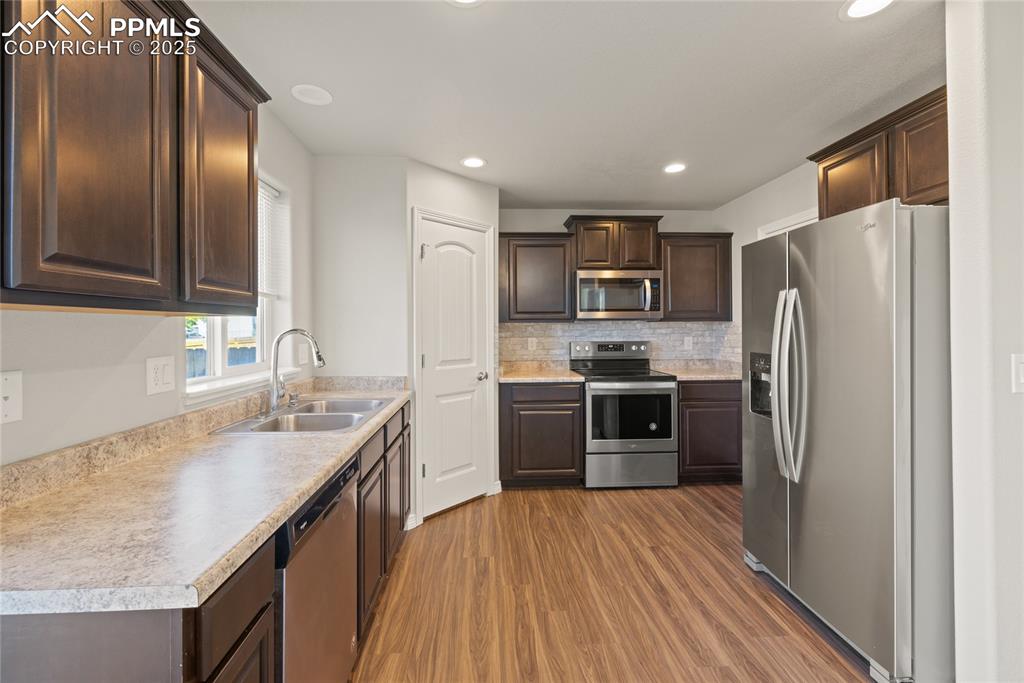 Image 12 of 24: Kitchen featuring appliances with stainless steel finishes, dark brown cabi