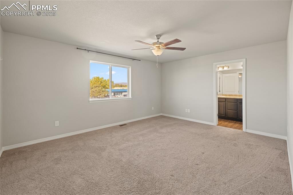 Image 16 of 24: Unfurnished bedroom with light carpet, ceiling fan, ensuite bath, and a tex