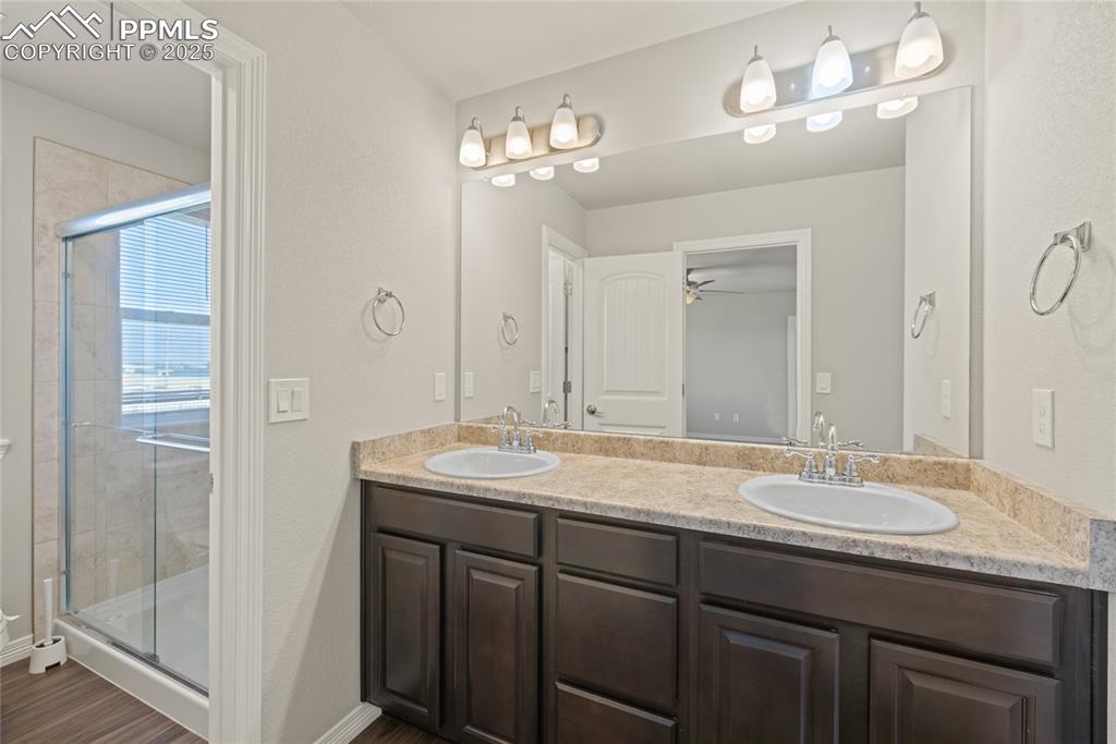 Image 18 of 24: Bathroom featuring a stall shower, double vanity, dark wood-style flooring,