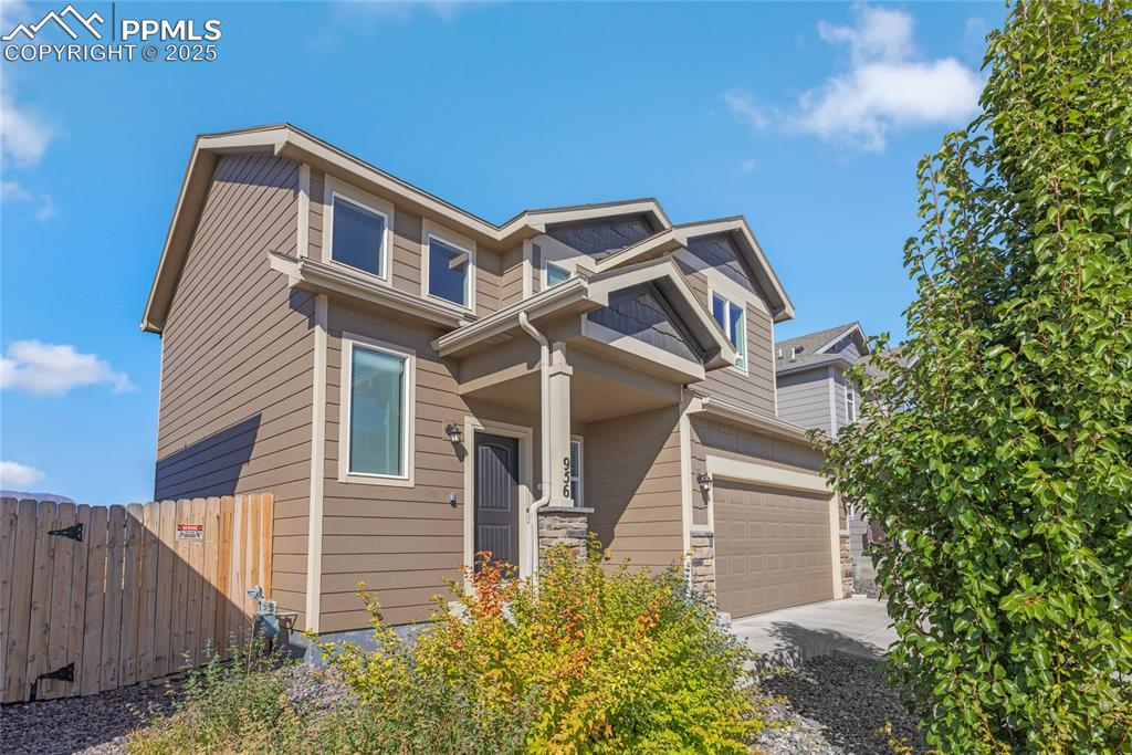 Image 2 of 24: View of front of home with stone siding, a garage, and driveway
