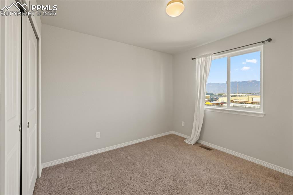Image 21 of 24: Unfurnished bedroom featuring a closet, light carpet, and a mountain view