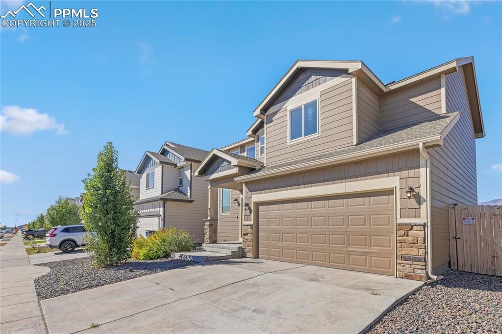 Image 3 of 24: Craftsman house featuring stone siding, a garage, concrete driveway, and ro