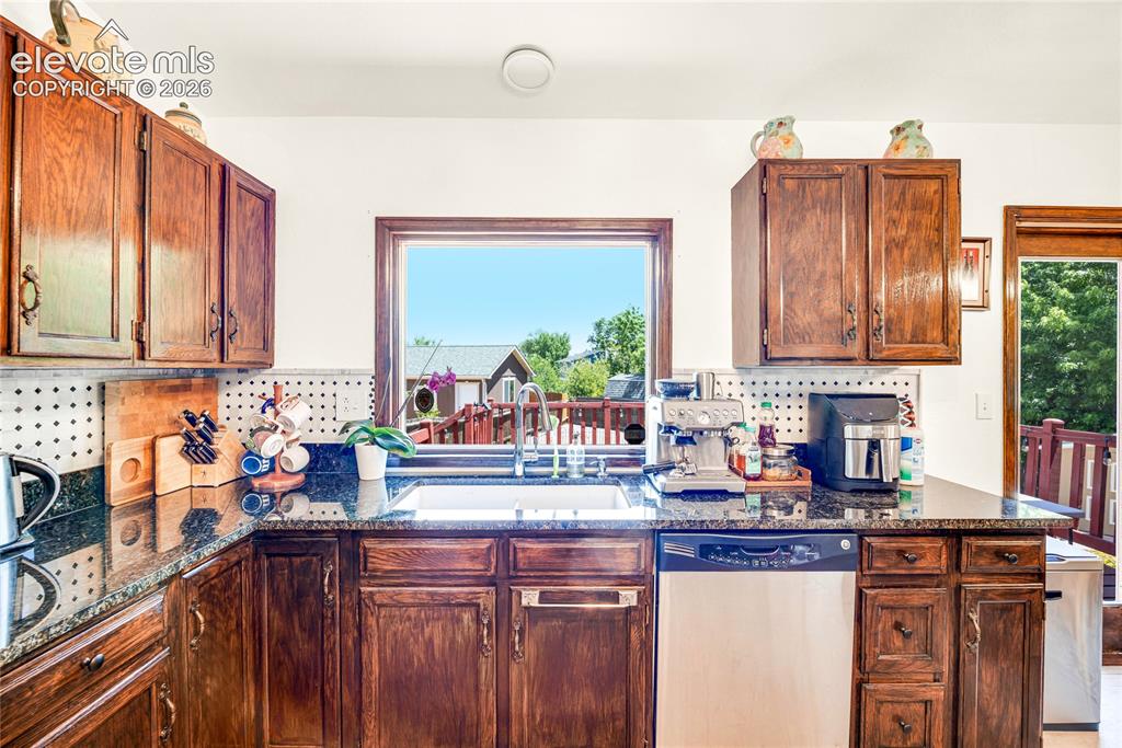 Image 12 of 46: Kitchen featuring wood-finish cabinetry, dark speckled countertops, a stain