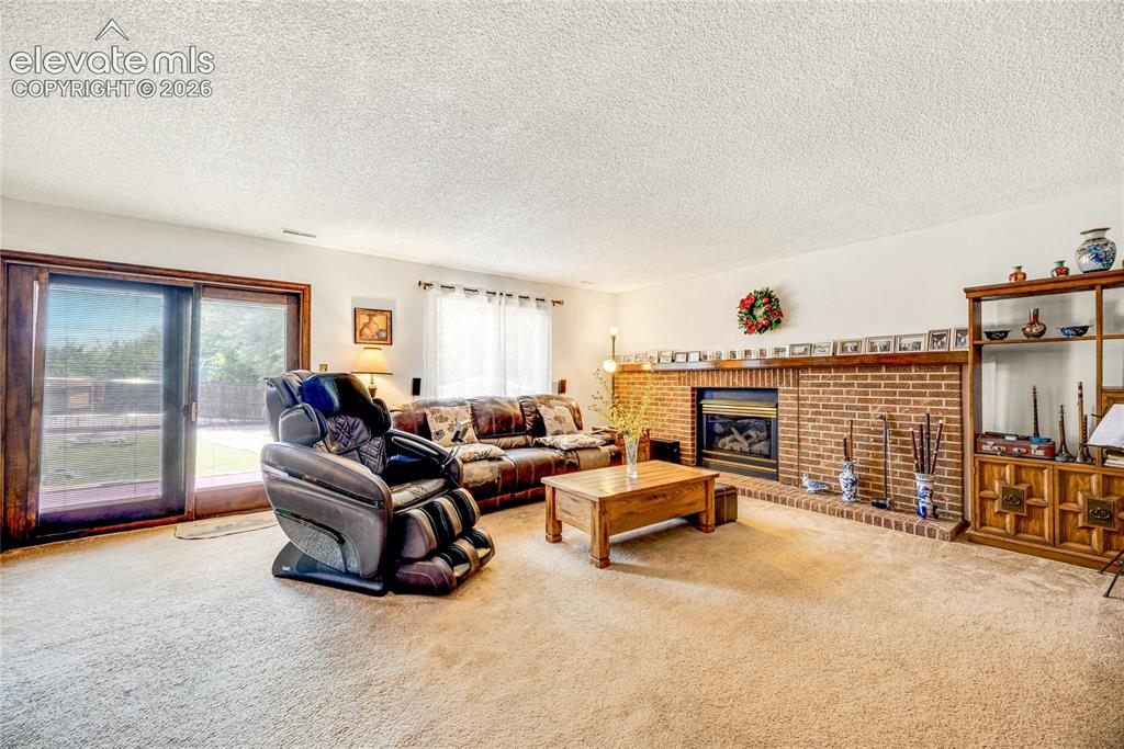 Image 24 of 46: Living area with a floor-to-ceiling brick fireplace surround and hearth, fe