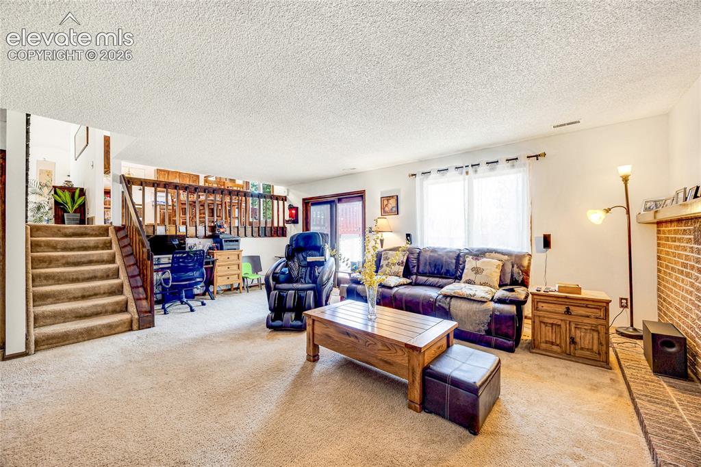 Image 25 of 46: Carpeted living area featuring a brick accent wall, a large window with whi