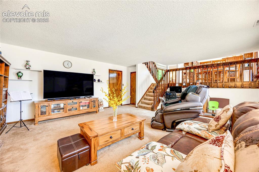 Image 26 of 46: Carpeted living space featuring a wood staircase with wood railing, a wood-