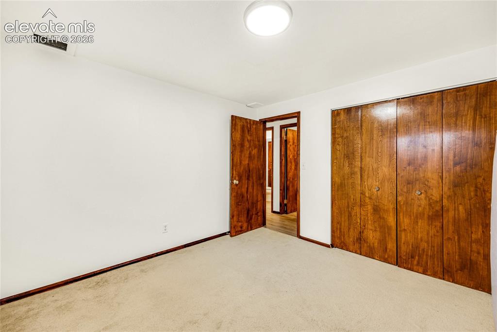 Image 30 of 46: Room featuring light-colored carpeting, white walls, and dark wood-finish t