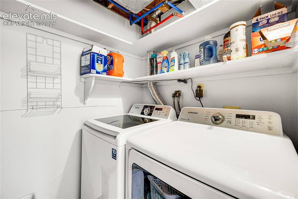 Image 31 of 46: Dedicated laundry area featuring a white top-load washer and front-load dry
