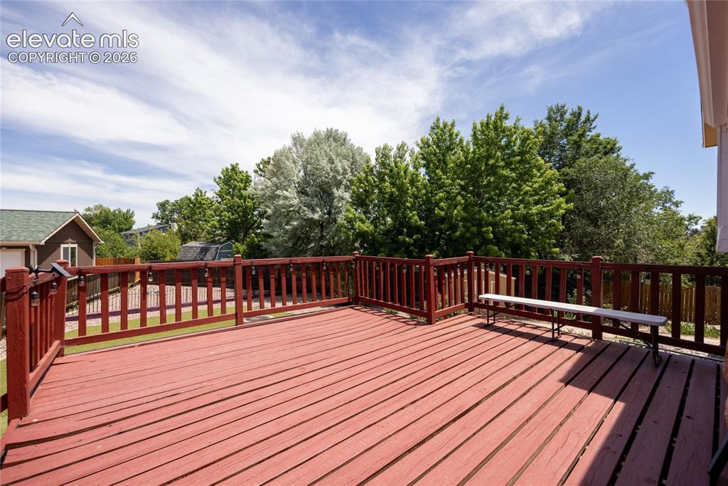 Image 34 of 46: Spacious outdoor wood-finish deck with a red stain and coordinating wood ra