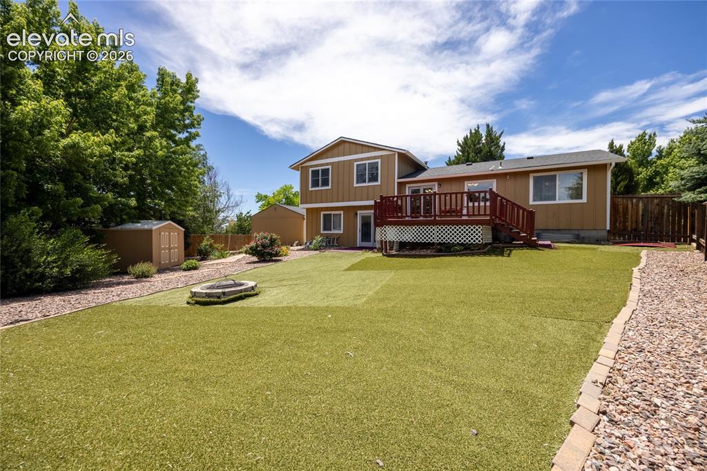 Image 36 of 46: Spacious backyard featuring artificial turf, a built-in fire pit, and a gra