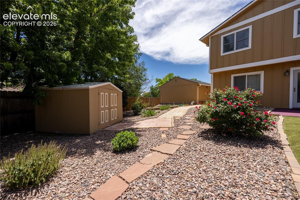 Image 38 of 46: Expansive yard featuring a flagstone and gravel pathway, a detached storage
