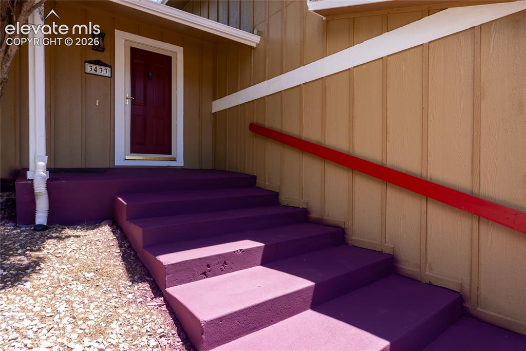 Image 4 of 46: Exterior featuring a bold red entry door, purple-painted concrete steps, an