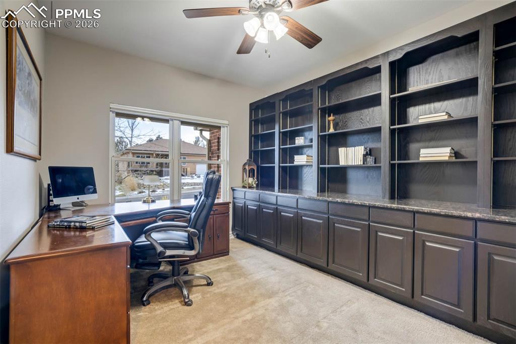 Image 16 of 50: Main floor large office with built-in cabinets and shelving. Ceiling fan w