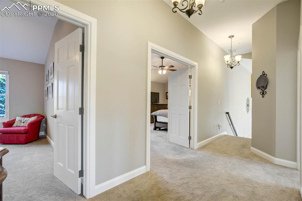 Image 19 of 50: Upstairs hallway with a chandelier, carpet and showing double doors into th