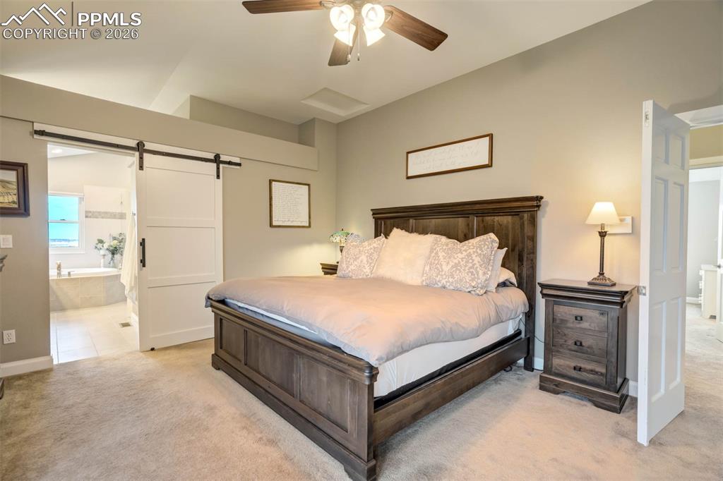 Image 22 of 50: Another view of the primary bedroom showing the barn door into the primary