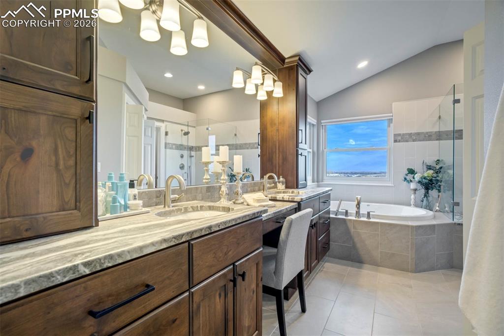 Image 24 of 50: Primary bathroom with marble countertops, double sinks and make-up desk are