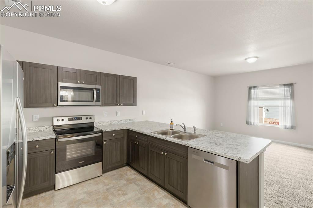 Image 12 of 27: Kitchen featuring a peninsula, appliances with stainless steel finishes, da
