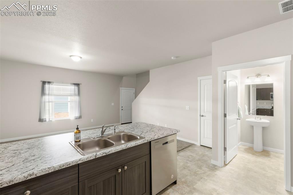 Image 13 of 27: Kitchen featuring dark brown cabinets and stainless steel dishwasher