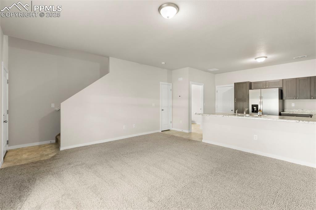 Image 9 of 27: Unfurnished living room featuring light carpet and stairway