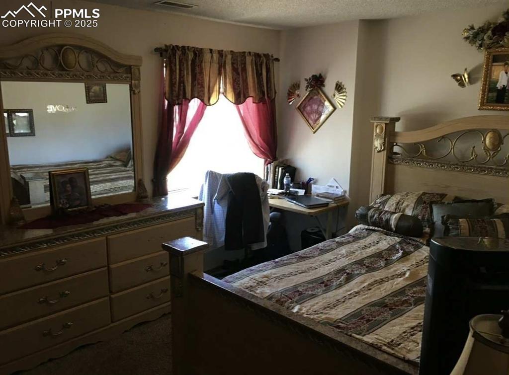 Image 13 of 20: Bedroom with dark colored carpet and a textured ceiling